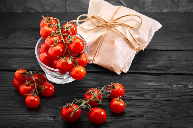 Fresh organic cherry tomatoes on a dark background, food delivery. Copy space.