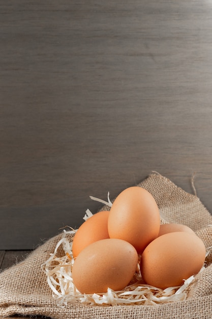 Fresh Organic eggs in burlap with dry grass on wood table.