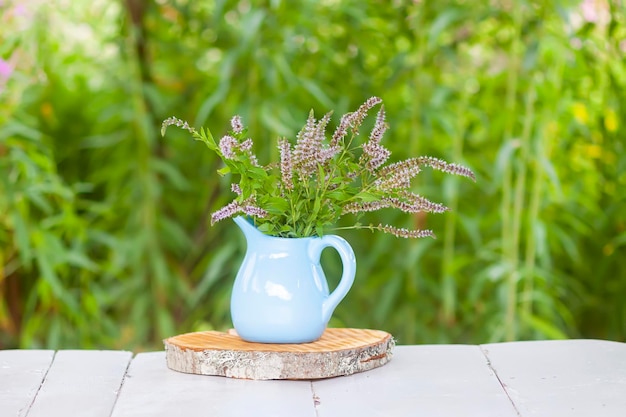 Fresh organic flowering mint plants for herbal tea Medical herbs Bouquet of medical flowers in a blue ceramic jug outdoors