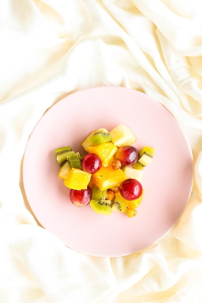 Fresh organic fruit salad on pink plate healthy nutrition and detox diet plan