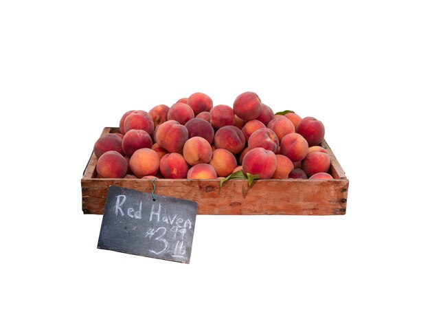 Fresh Organic peaches in wooden crate with black colour wooden price sign isolated on white