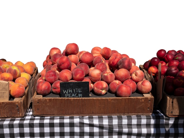 Fresh Organic peaches in wooden crate with black colour wooden price sign on table isolated on white