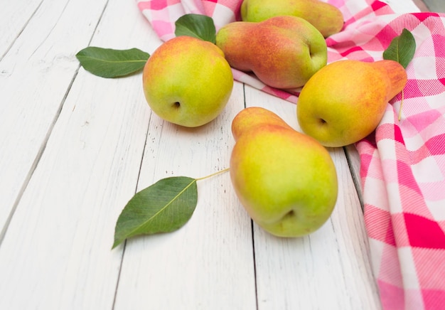 Fresh organic pears in a white basket on a white wooden background. Top view.