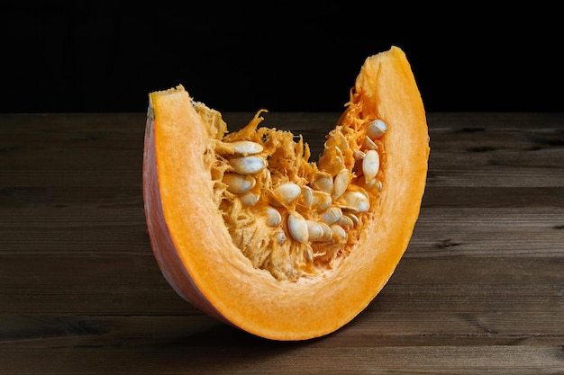 Fresh organic pumpkin slice with seeds on a dark background