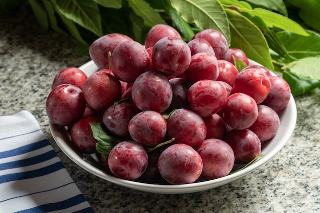 Fresh organic red plums in bowl