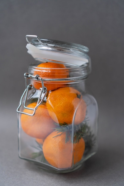 Fresh organic tangerines with spruce branches in a jar