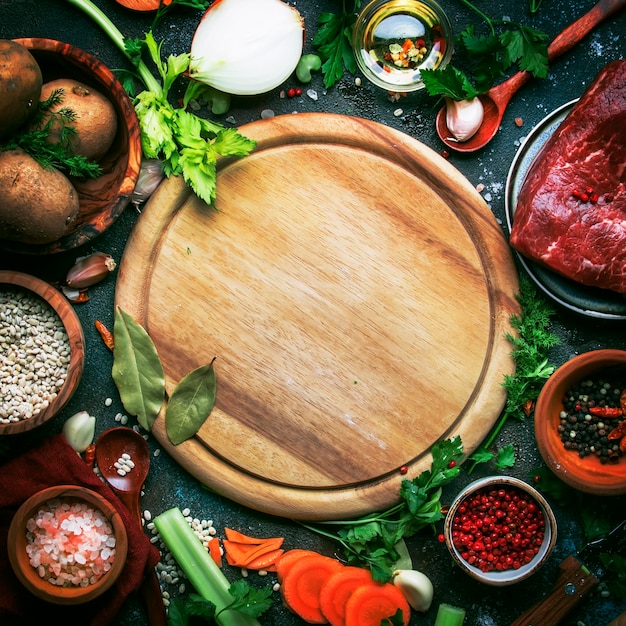 Fresh organic vegetables ingredients spices and meat for soup or broth on vintage kitchen table..