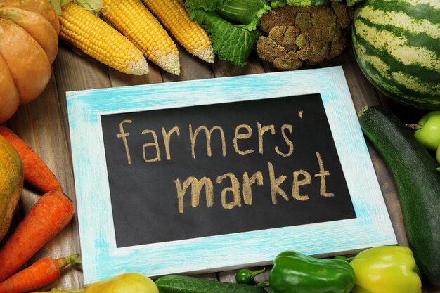 Photo fresh organic vegetables with chalkboard on wooden table close up