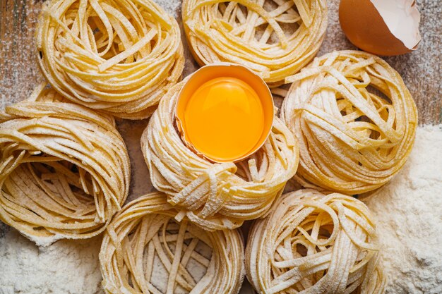 Fresh pasta food. Homemade Italian pasta cooked on a wooden table in a rustic style decorated with egg and flour.