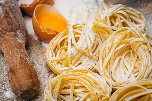 Fresh pasta food. Homemade Italian pasta cooked on a wooden table in a rustic style decorated with egg and flour.