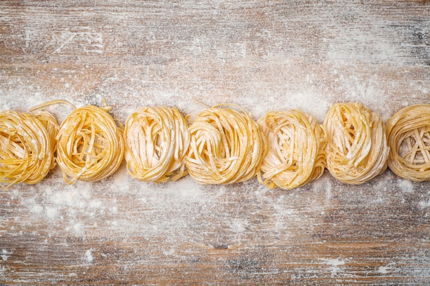 Fresh pasta food. Homemade Italian pasta cooked on a wooden table in a rustic style decorated with egg and flour.