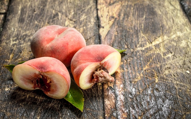 Fresh peaches with leaves. On a wooden table.