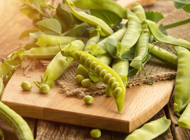 Fresh peas and their pods on an old wooden table rustic background with peas