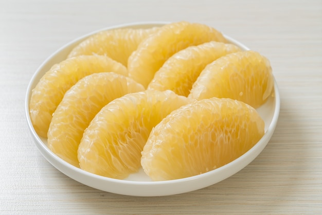 Fresh peeled pomelo, grapefruit or shaddock on white plate