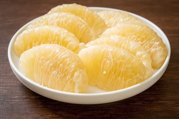 Fresh peeled pomelo, grapefruit or shaddock on white plate