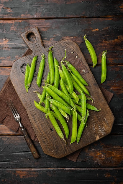 Fresh picked green pea on old dark wooden table background top view flat lay