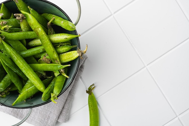 Fresh picked green pea on white ceramic squared tile table background top view flat lay with copy space for text