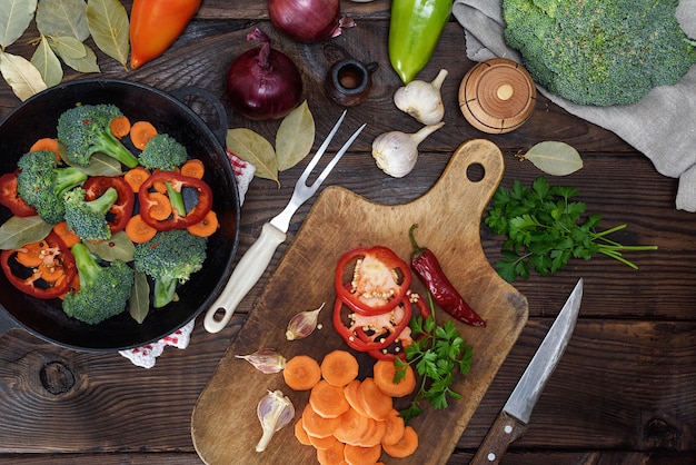 Fresh pieces of carrots, broccoli and red pepper on wooden kitchen board