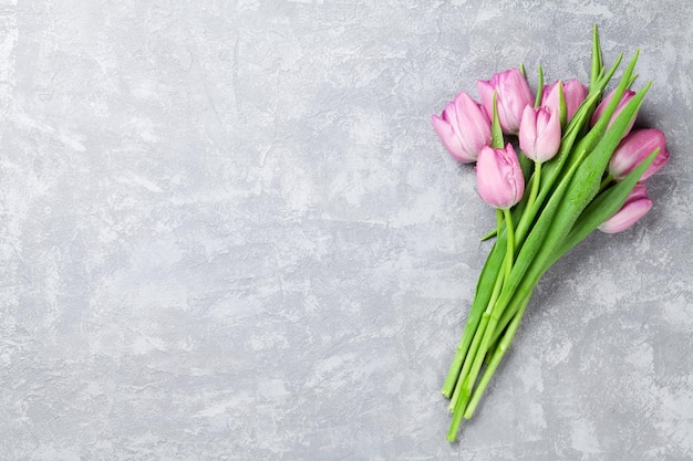 Fresh pink tulip flowers on stone table