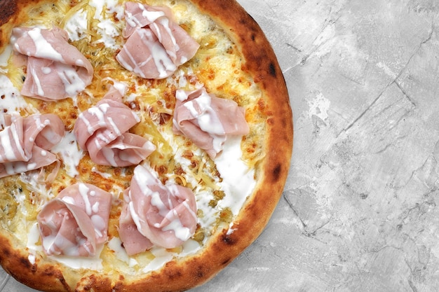 Fresh pizza with ham and pineapple on stone table in restaurant