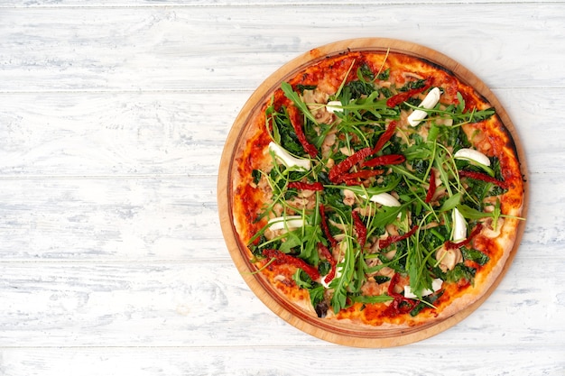 Fresh pizza with herbs and sun dried tomatoes on gray table