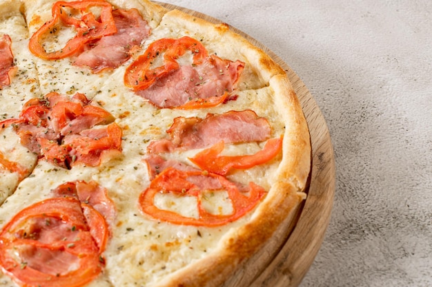 Fresh pizza with meat and ham on the concrete background