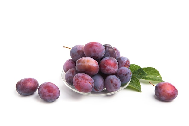 Fresh plum fruits with leaves on bowl