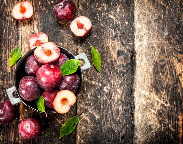 Fresh plums in a bowl. On a wooden background.