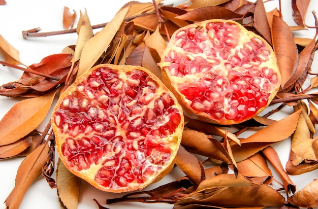 Fresh Pomegranates on background of autumn leaves