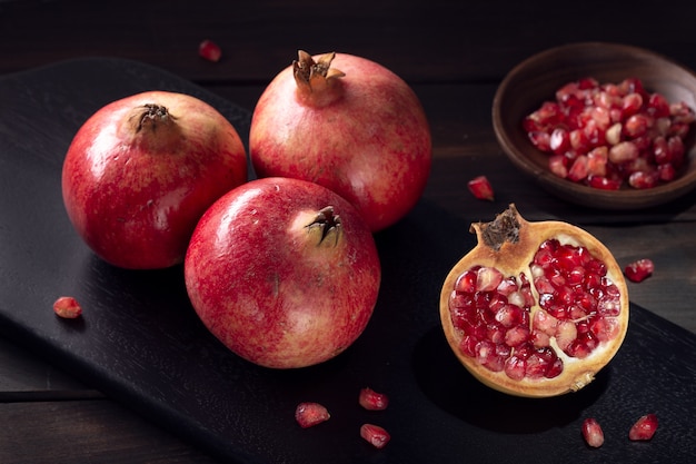 Fresh Pomegranates and sliced pomegranate with seeds on wooden table