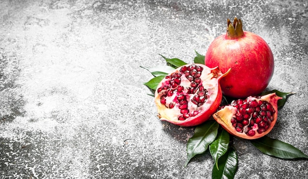 Fresh pomegranates with green leaves on rustic background