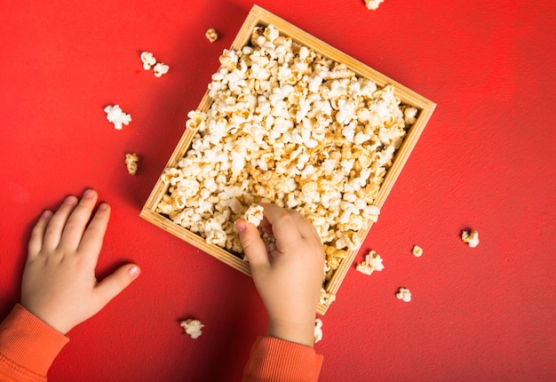 Fresh popcorn spilled out of the box on red