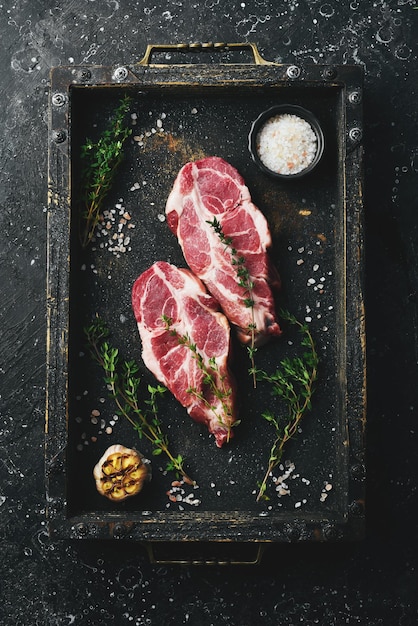 Fresh pork Two pork steaks Top view On a black stone background