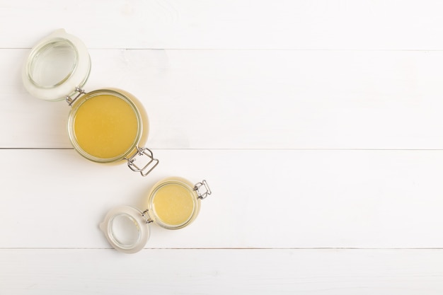 Photo fresh poultry broth in a glass jar on a white table. top view with copy space