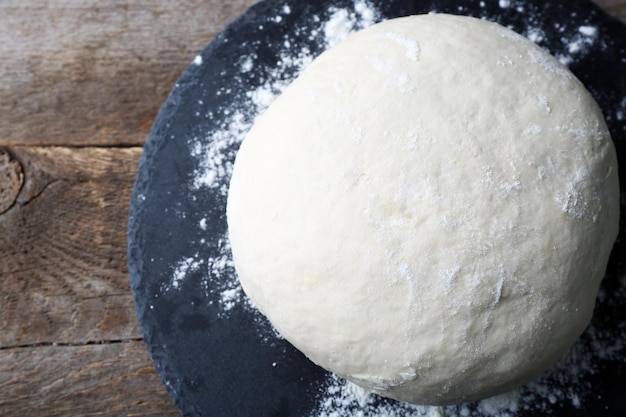 Fresh prepared dough on a wooden board close up