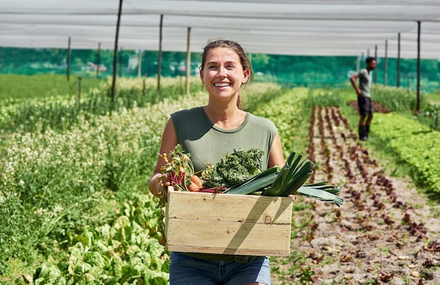 Fresh produce coming right up Portrait of an attractive young woman carrying a crate full of vegetables outdoors on a farm