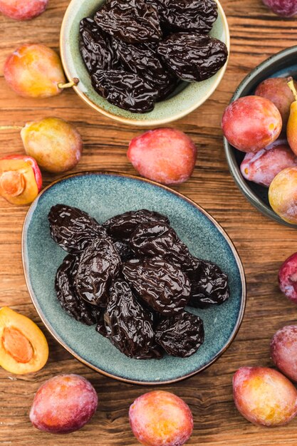 Photo fresh prune and dried prune on wooden board