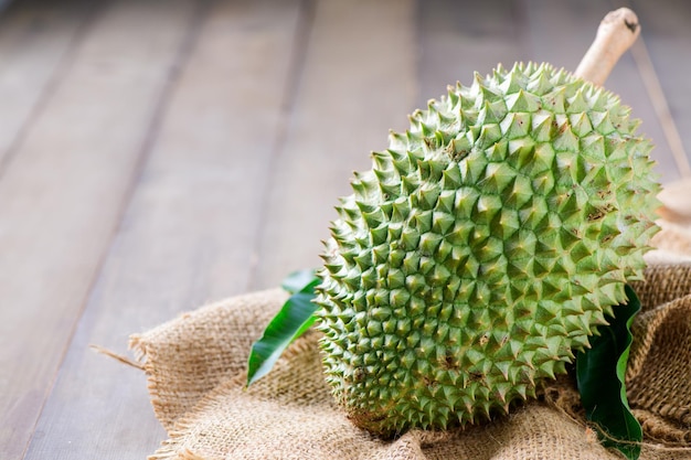 Fresh Puangmanee durian on sack and wood background It's a small durian