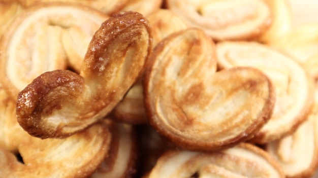 Fresh puff pastry palm cookies in the shape of a heart. Classic French pastries. Pig ear, elephant ear cookies, French hearts. View from above.