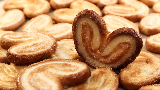 Fresh puff pastry palm cookies in the shape of a heart. Classic French pastries. Pig ear, elephant ear cookies, French hearts.