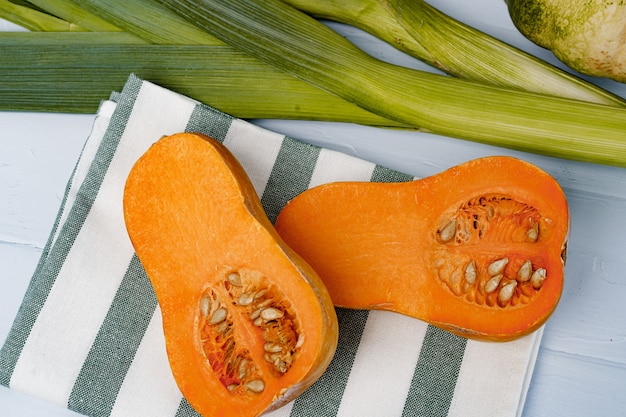 Fresh pumpkin and leek on white table close up