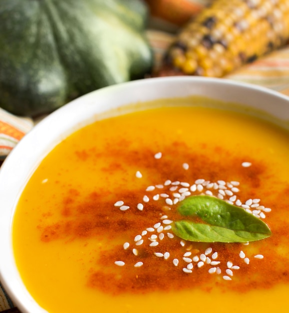 Fresh pumpkin soup with pumpkins and corn close up