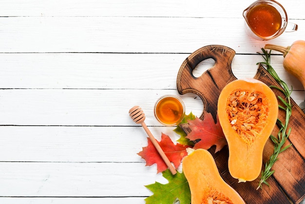 Fresh pumpkin with honey on white wooden background Autumn food Top view Free copy space