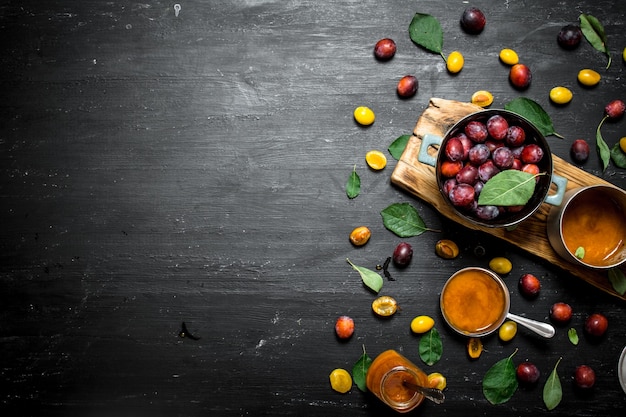 Fresh puree of ripe plums with green leaves. On a black chalkboard.