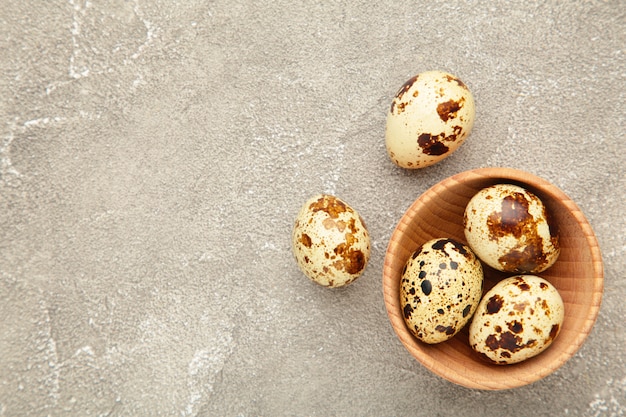 Fresh quail eggs in bowl on grey concrete background