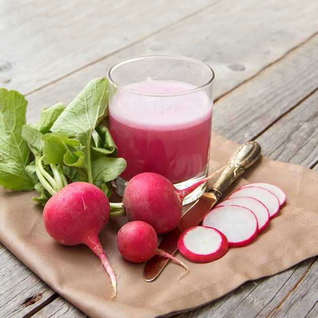 Fresh radish juice in a glass on a wooden table close up