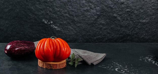 Fresh Raf Coeur De Boeuf tomato and eggplant with oregano on a grey background textile