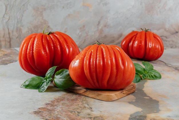 Fresh Raf Coeur De Boeuf tomatoes and basil on a brown background