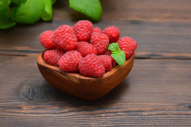 Fresh raspberries and mint leaves on a wooden background close up