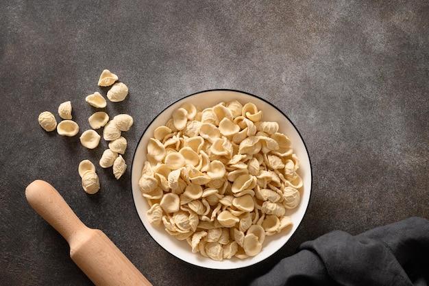 Fresh raw apulian pasta orecchiette made from whole wheat flour on a dark table top view